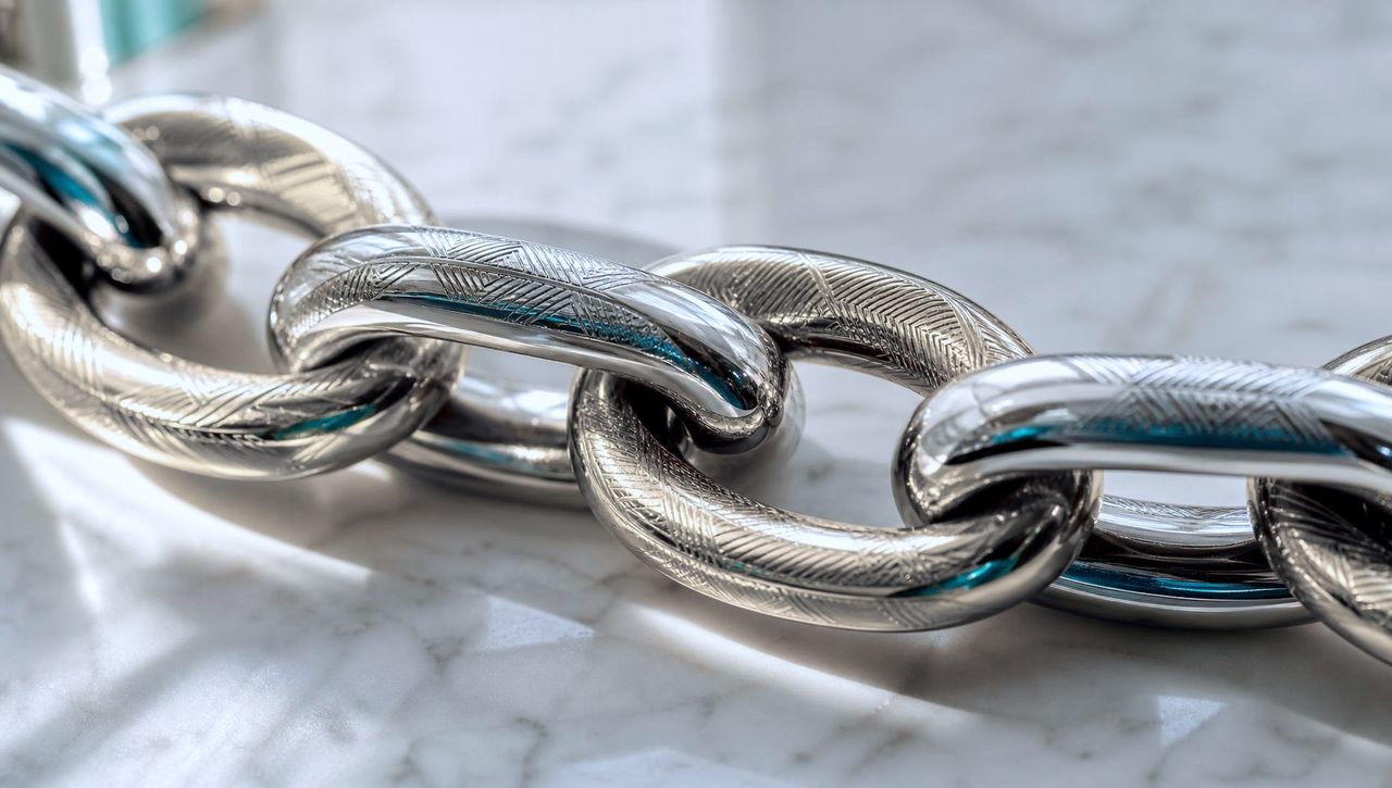 Interlocking engraved chain links on marble, representing the hash-chained audit ledger